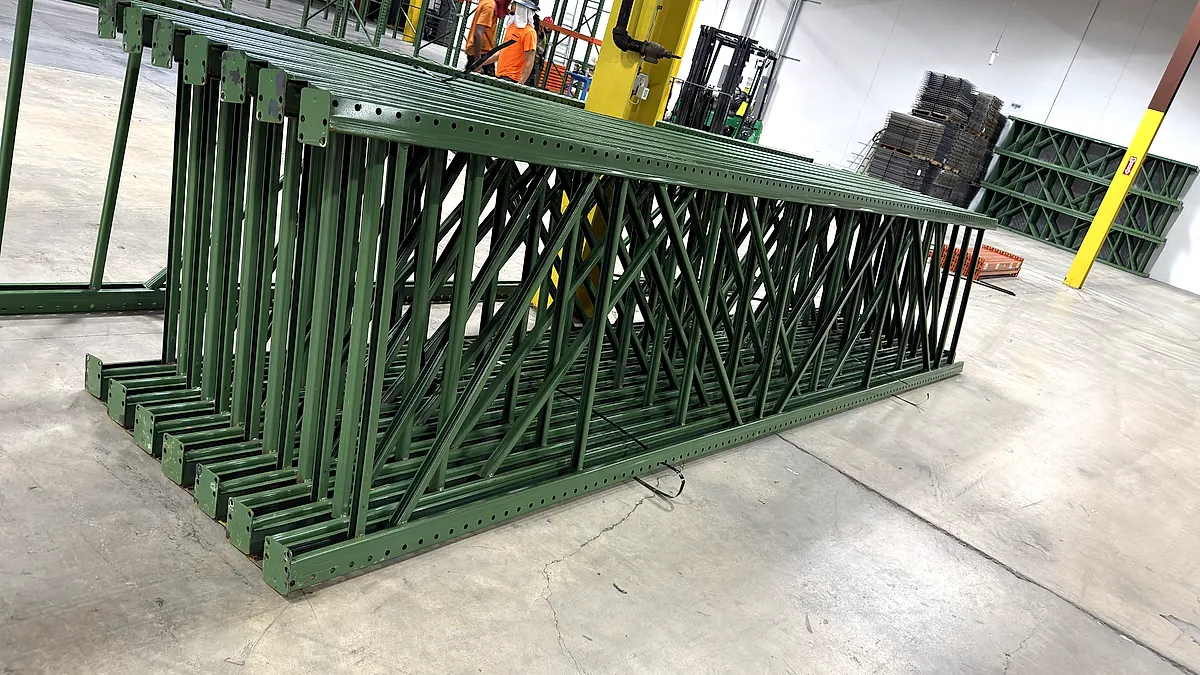 Pallet rack upright frames laid out on the floor before standing