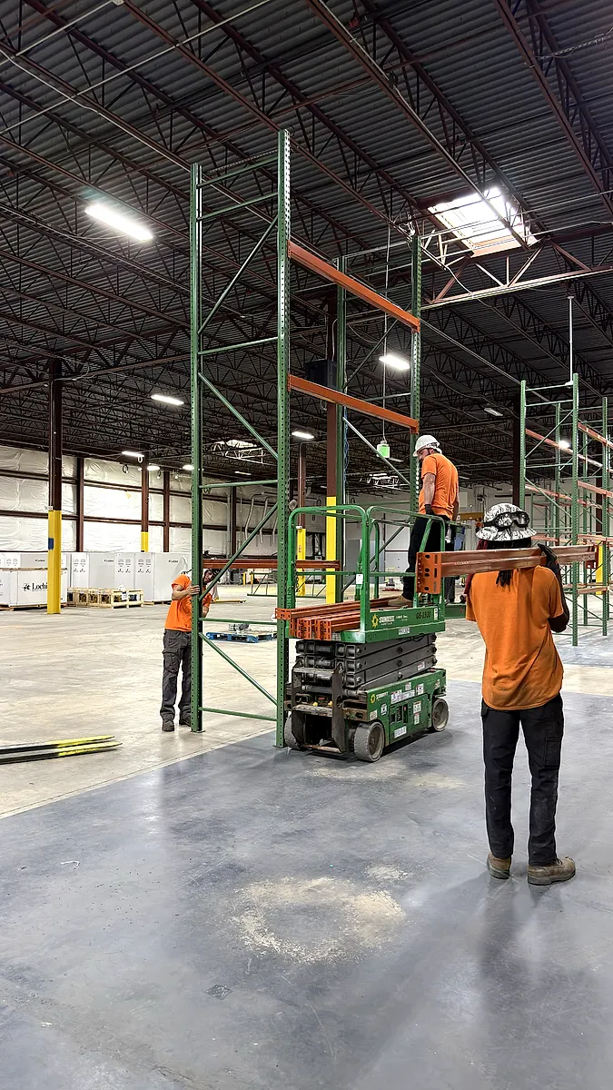 Installer carrying a pallet rack beam to the next bay