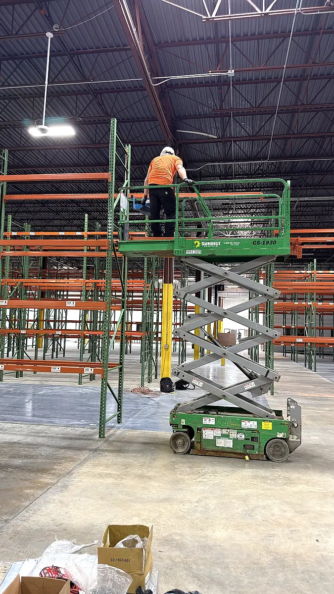 Scissor lift raised to the top beam level of new pallet rack
