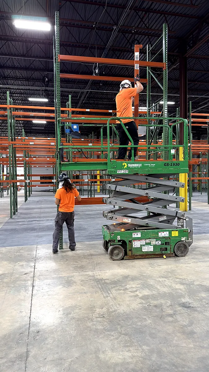 Alliance crew installing upper pallet rack beams from a scissor lift