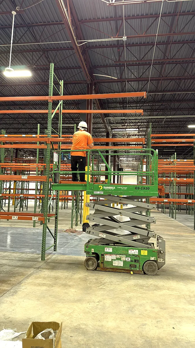 Installer on a scissor lift fitting upper rack beams