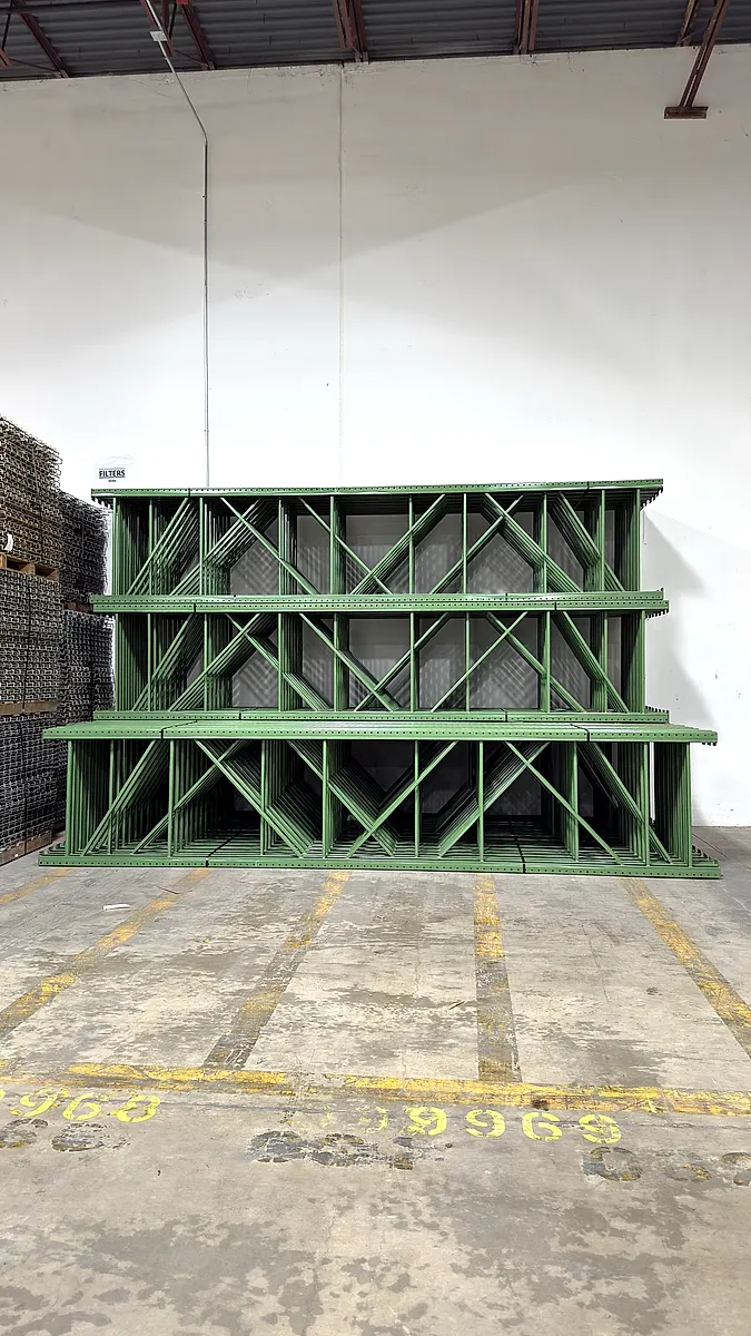 Pallet rack upright frames stacked against a wall